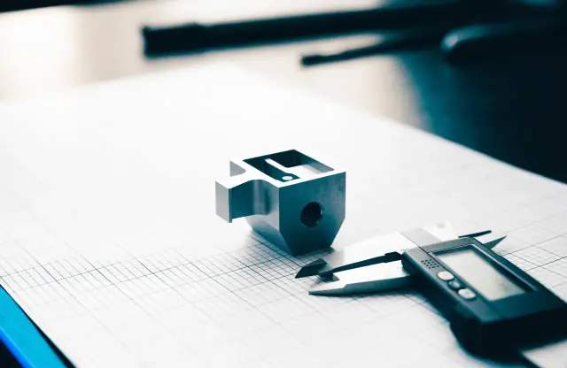 Gefrästes Aluminiumgehäuse mit Messschieber auf Millimeterpapier